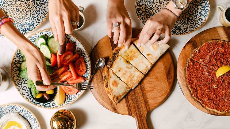 Lebanese manoush at Mt Lewis Pizzeria hands of two people reaching for food of Lebanese manoush and salad