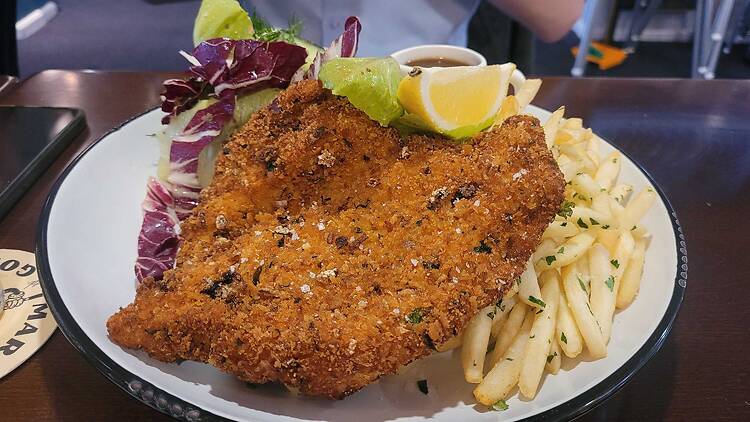 A chicken schnitzel with chips and salad
