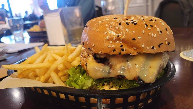 A chicken burger with melted cheese, and chips on the side