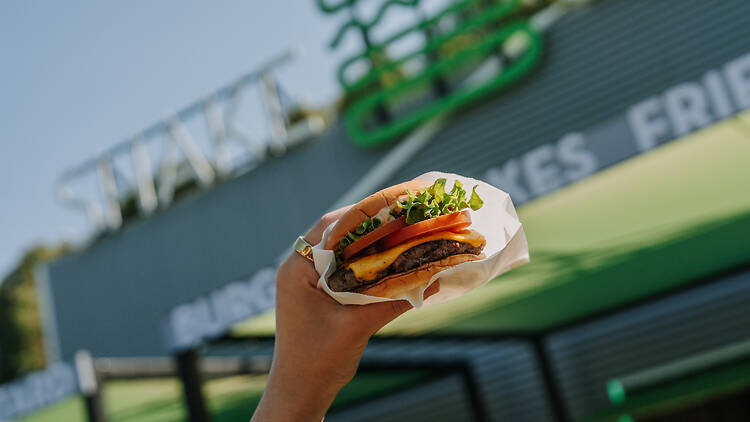 A hand holding a Shake Shack burger