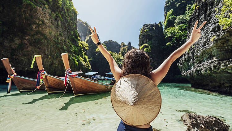 Young woman on a beautiful beach in Thailand with longtail boats, Phi Phi Island Young woman on a beach in Thailand in front of longboats