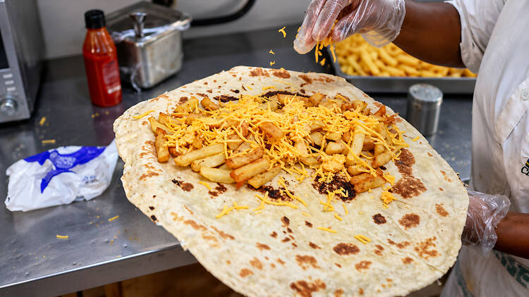 Generous handfuls of chips and cheese go into a roti in the Johnny’s kitchen.
