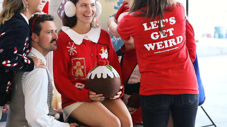 people wearing christmas outfits pose for photo