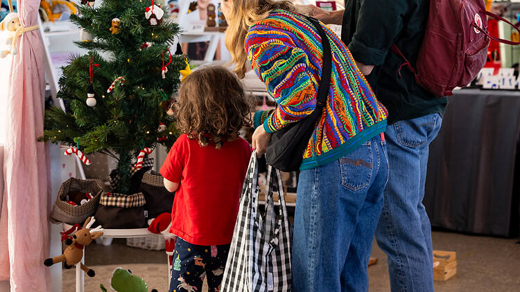 a family of dad, mum and child look at a christmas tree