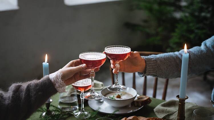 Two people 'cheers' with a cocktail