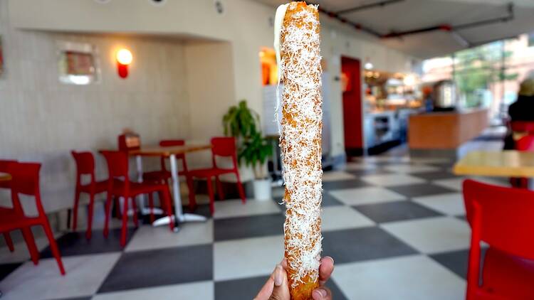 A person holding a massive mozzarella stick