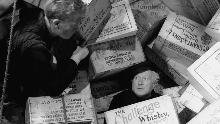 Still from the film Whisky Galore! of two men buried under crates of whisky